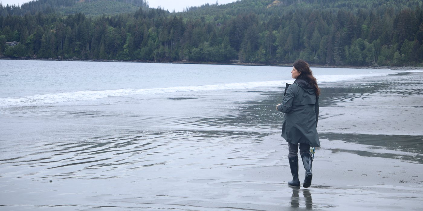 Brandy Nielson walking along a quiet Vancouver Island beach in a rain jacket