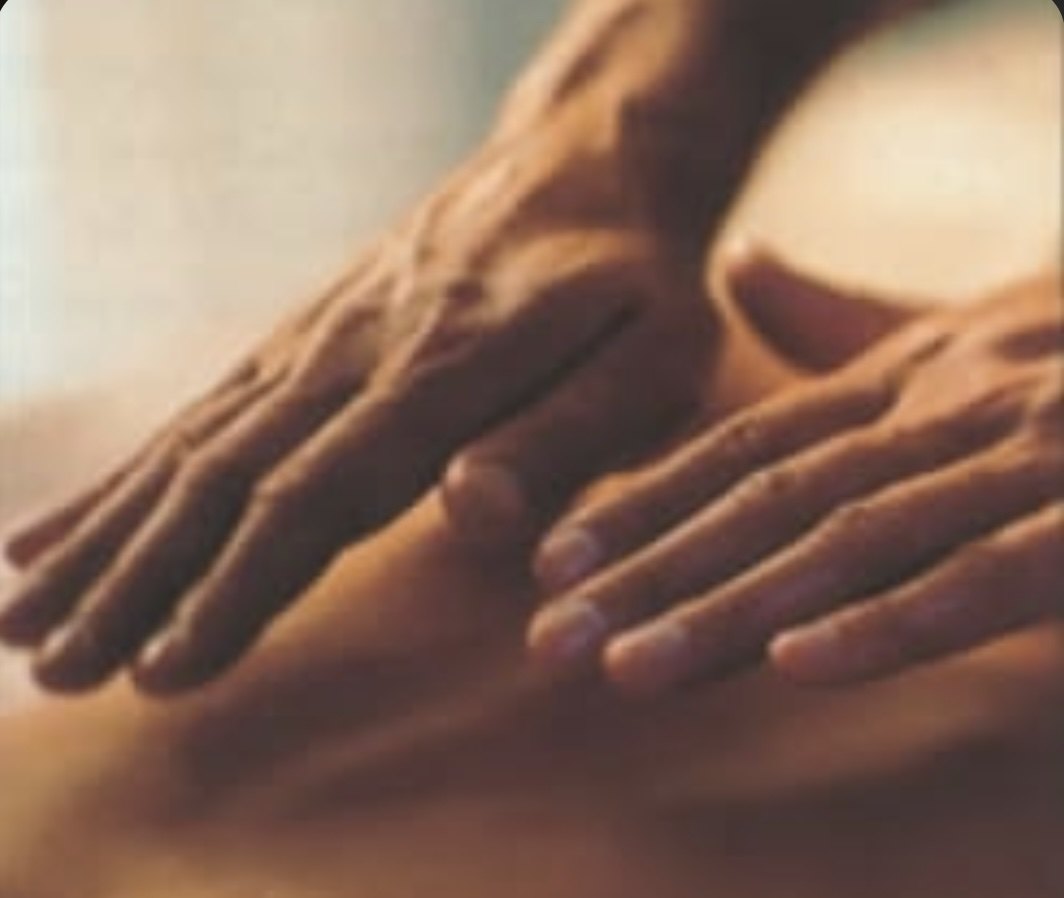 Two hands resting softly on a person's back in warm light